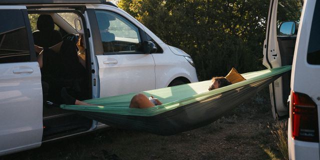 Mann liegt in einer Hängematte zwischen Campern