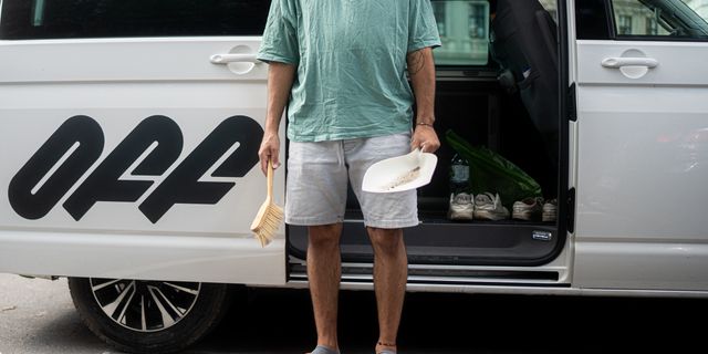 Mann steht mit Schaufel & Besen vor Camper