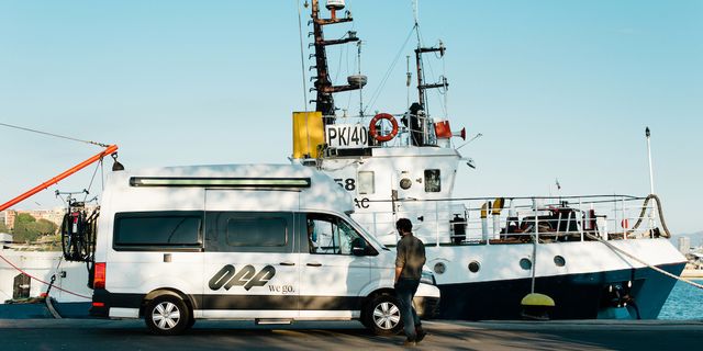 Ein VW Grand California 600 Van steht am Hafen, ein Mann geht darauf zu.