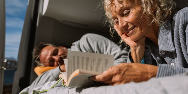 Frau liest Buch im Camper