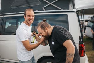 Lukas (Team Lead Stations) und Tim (Process Manager) stehen lachend vor einem CamperBoys Camper.